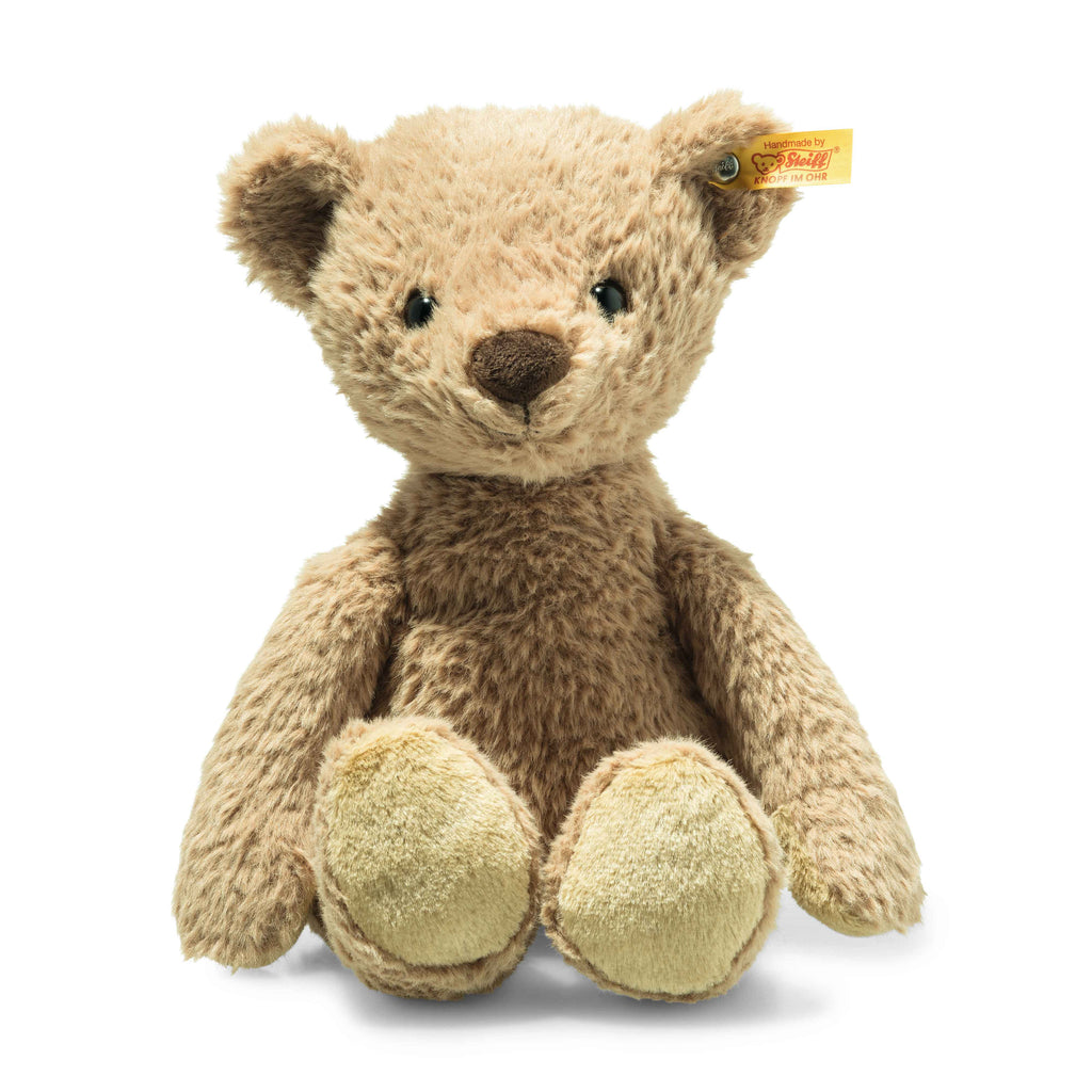 The Thommy Teddy Bear Brown Plush Toy, 12 Inches, sits upright with light brown fur. It has a dark brown nose, round black eyes, and a small yellow tag in one ear. Its handmade plush paws are lighter beige.