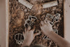 A child’s hands play with the Construction Cutter Set - Eco Playdough Tool in a tray filled with brown dirt, using the playdough tools to shape a construction-themed scene. Several other vehicle cutters and rolling pins from the set are also visible on the dirt surface, making this sensory play experience engaging and creative.
