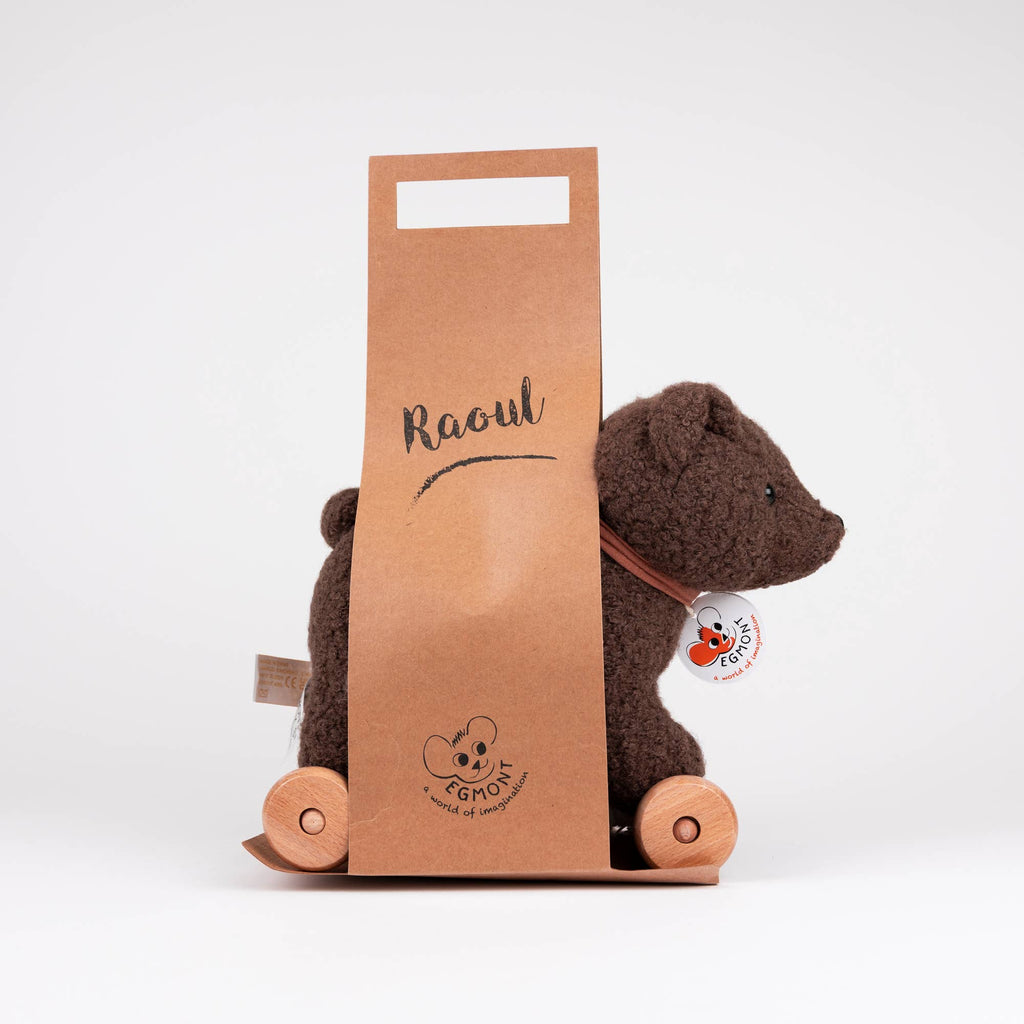 The Pull-Along Raoul is a brown plush bear pull-along toy on wooden wheels, partially nestled inside a brown cardboard holder labeled "Raoul." The bear, made by Egmont Toys, has a tag attached to its neck and is photographed against a plain white background.