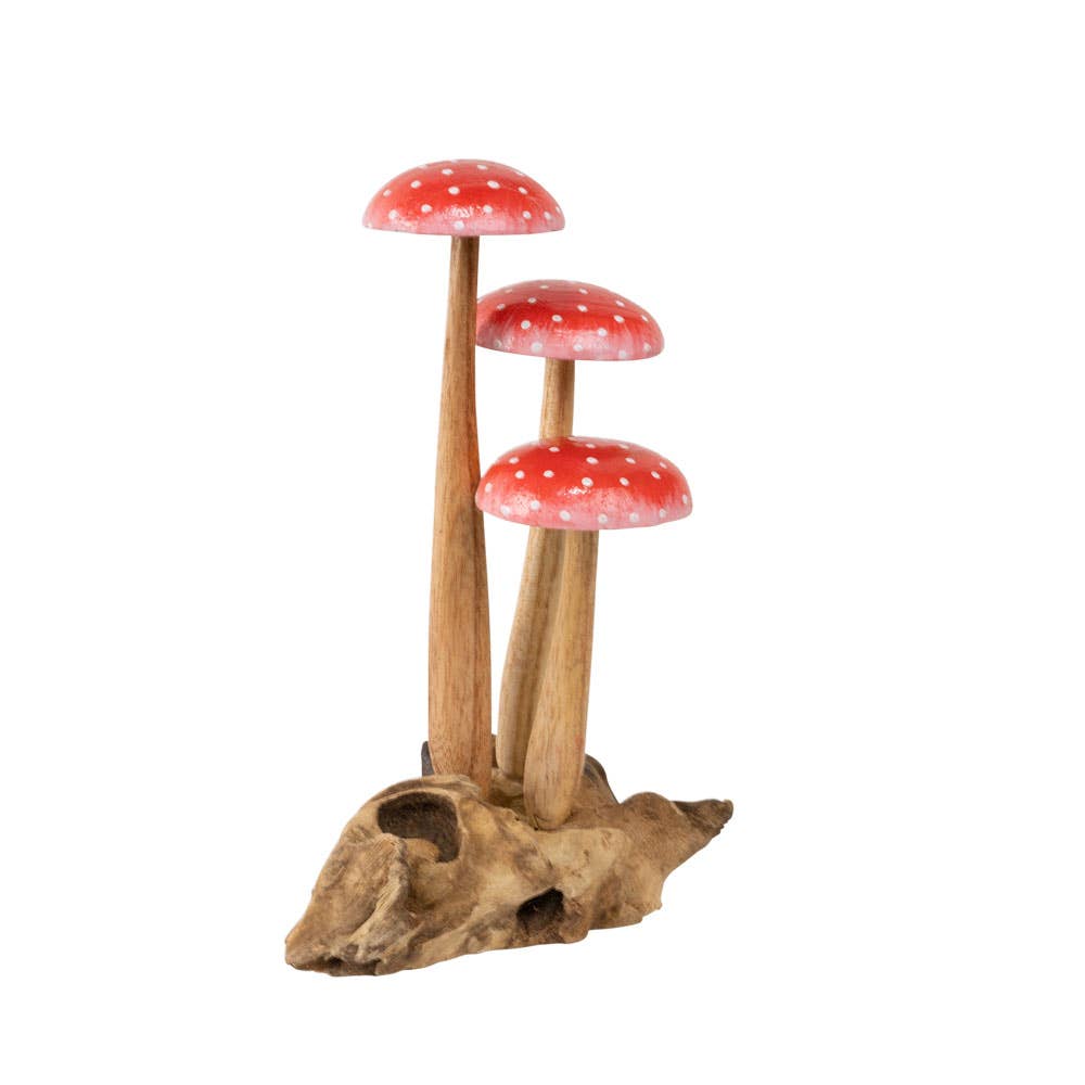 The Small Wooden Red Mushroom Trio features three wooden red mushrooms with white spots and tall wooden stems, all grouped together on a textured, light brown driftwood base. This decorative figurine adds a whimsical touch to any space.