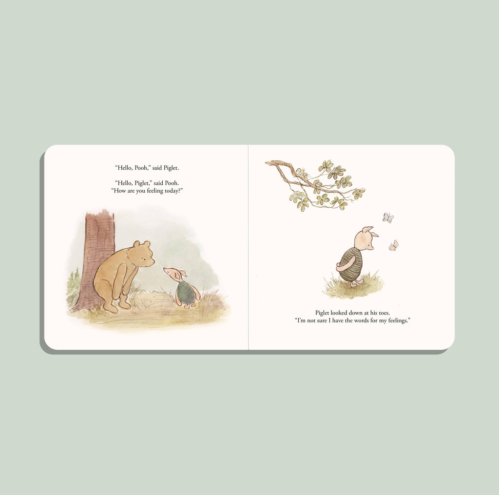 An open Winnie-the-Pooh: Finding Feelings board book shows Pooh and Piglet talking in a forest. Piglet glances down as butterflies flutter by on a light green background, helping toddlers explore emotions.