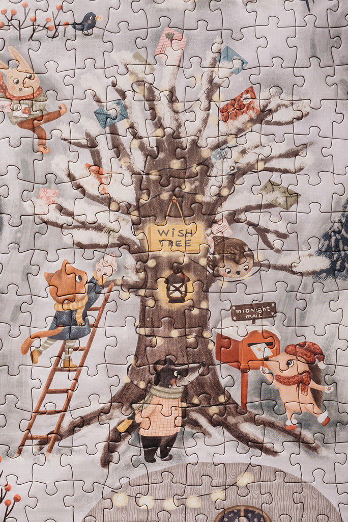 The Midnight Mail 500 Piece Puzzle features woodland animals around a moonlit Wish Tree, hanging flags and mailing letters in a snowy, festive setting.