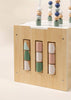 The Wooden Activity Cube features three vertical rows of rotating blocks with pastel geometric shapes and colorful beads on white wires, offering engaging play and helping toddlers develop fine motor skills.
