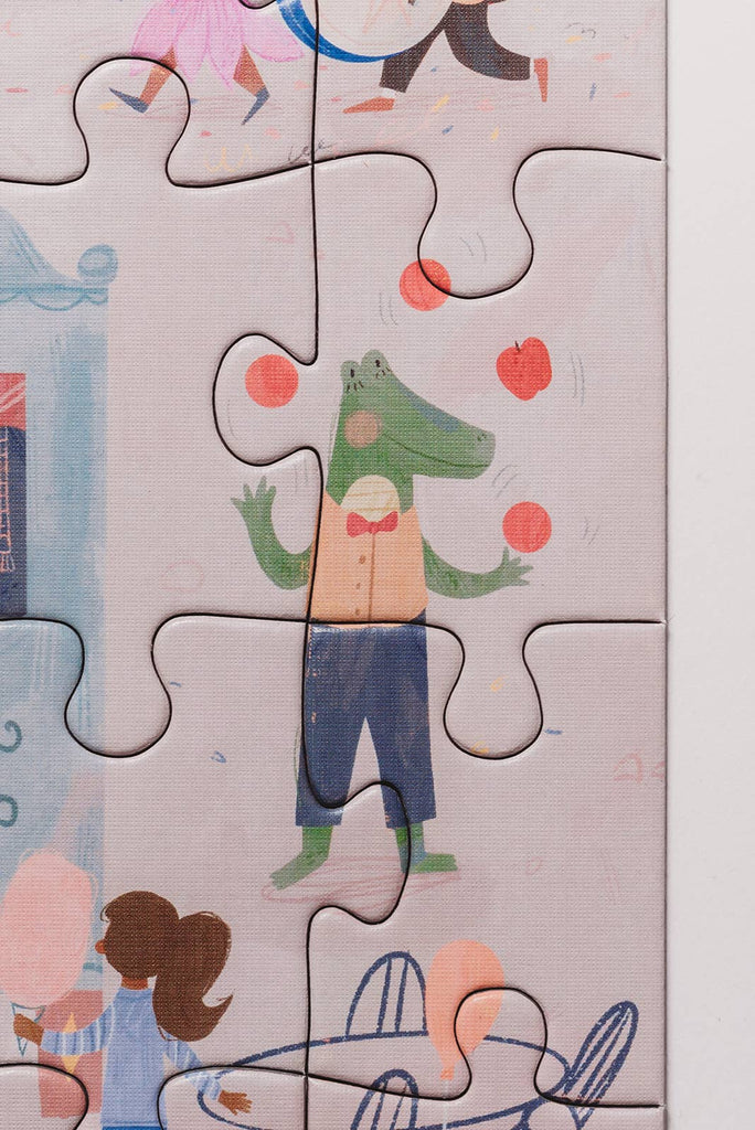 A Carnival of Wonders 100 Piece Puzzle features a cartoon crocodile in a bow tie juggling red balls, plus other colorful illustrations. Made from recycled materials, it's perfect for kids ages 5+.