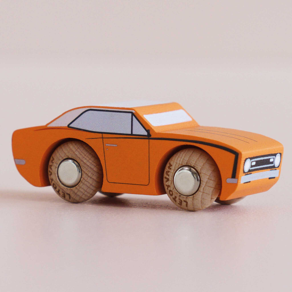 The No. 22 GT125 Cami, a small orange classic American muscle toy car with black details and wooden wheels, made in England, is displayed on a light surface.