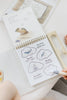 A hand uses a water pen on a Winnie-the-Pooh: Pooh’s Birthday Surprise (Water Reveal) spiral-bound book, uncovering illustrations of a whale, bird, and boat hidden within clouds in this no-mess activity.