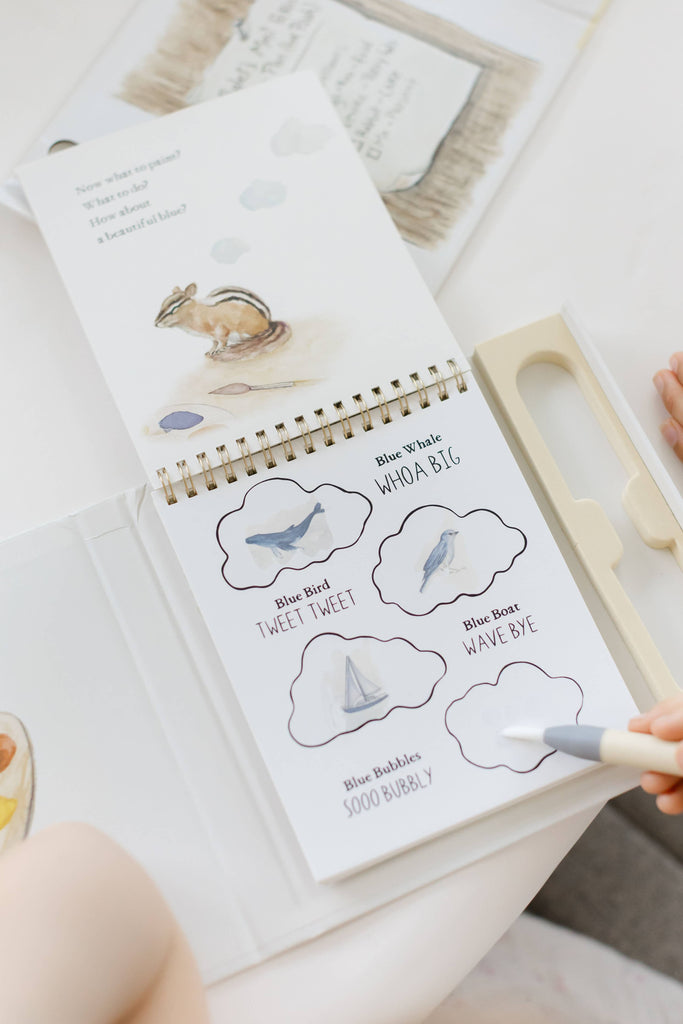 A hand uses a water pen on a Winnie-the-Pooh: Pooh’s Birthday Surprise (Water Reveal) spiral-bound book, uncovering illustrations of a whale, bird, and boat hidden within clouds in this no-mess activity.