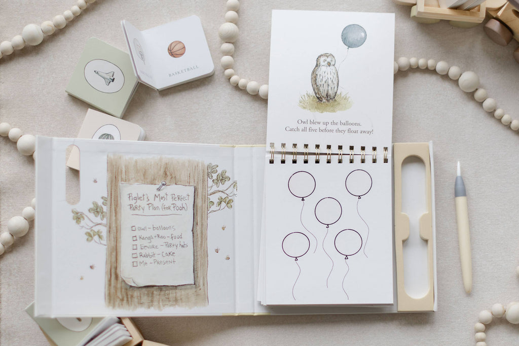 Open spiral-bound Winnie-the-Pooh: Pooh’s Birthday Surprise (Water Reveal) book showing an illustration of Owl with a balloon and a party plan checklist, with a stylus pen nearby.