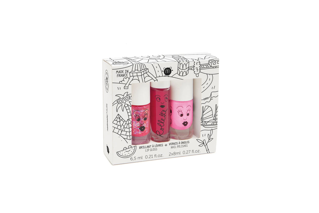 Three cylindrical Nailmatic - 2 Nail Polish + 1 Lipgloss Set - World Tour tubes with whimsical faces and floral designs, packaged in a box with black and white doodle illustrations, labeled in French and English.