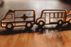 Wooden cutouts of an ambulance and a school bus from our Service Vehicle Cutter Set - Eco Playdough Tool are displayed side by side on a wooden surface, sunlight casting shadows behind them—ideal for sensory play or as eco-friendly playdough tools.