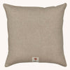 The Coral & Tusk Tree Trimmers Wreath Pillow is a square beige throw pillow with subtle texture and a small fabric tag bearing a tree-like red design—an ideal, understated choice for Christmas decor.
