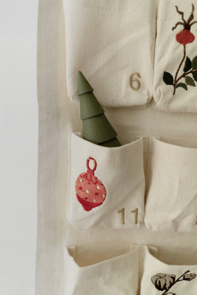 A green, cone-shaped tree sits in a fabric pocket with a red ornament and number 11, part of the Sabo Concept Christmas Cotton Advent Calendar featuring visible numbers 6 and 11.