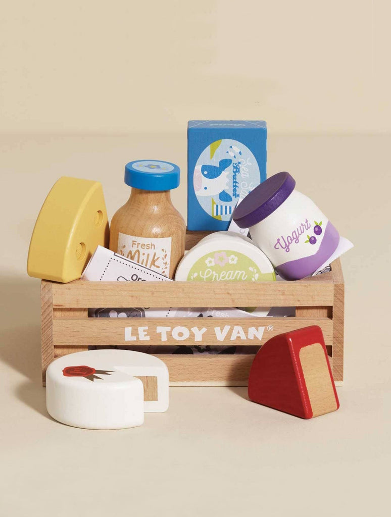 The Cheese & Dairy Wooden Market Crate includes assorted toy dairy items—cheese wedges, milk, cream, butter, and yogurt—in a colorful wooden crate for pretend play and learning.
