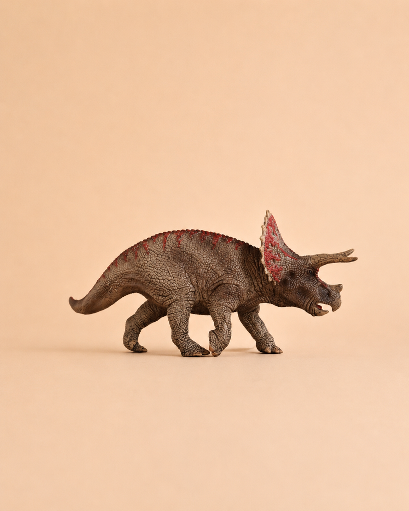 The Schleich Triceratops Dinosaur Toy features a textured brown body with red markings and stands against a plain beige background, making it an ideal educational figurine for collectors and fans of dinosaur toys.