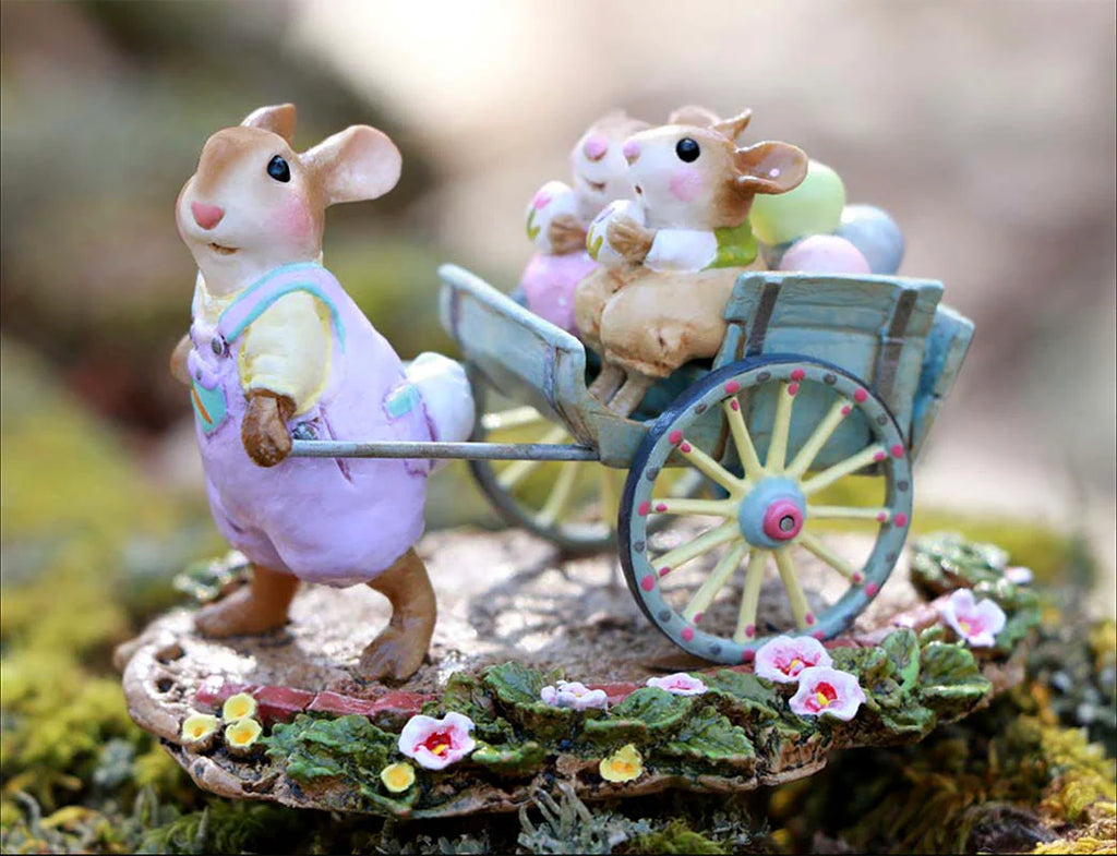 The Wee Forest Folk Tiny Collectible - Easter's on its Way features a hand-sculpted mouse in purple overalls pulling a blue cart with two smaller mice and colorful eggs, surrounded by flowers. Not a toy.