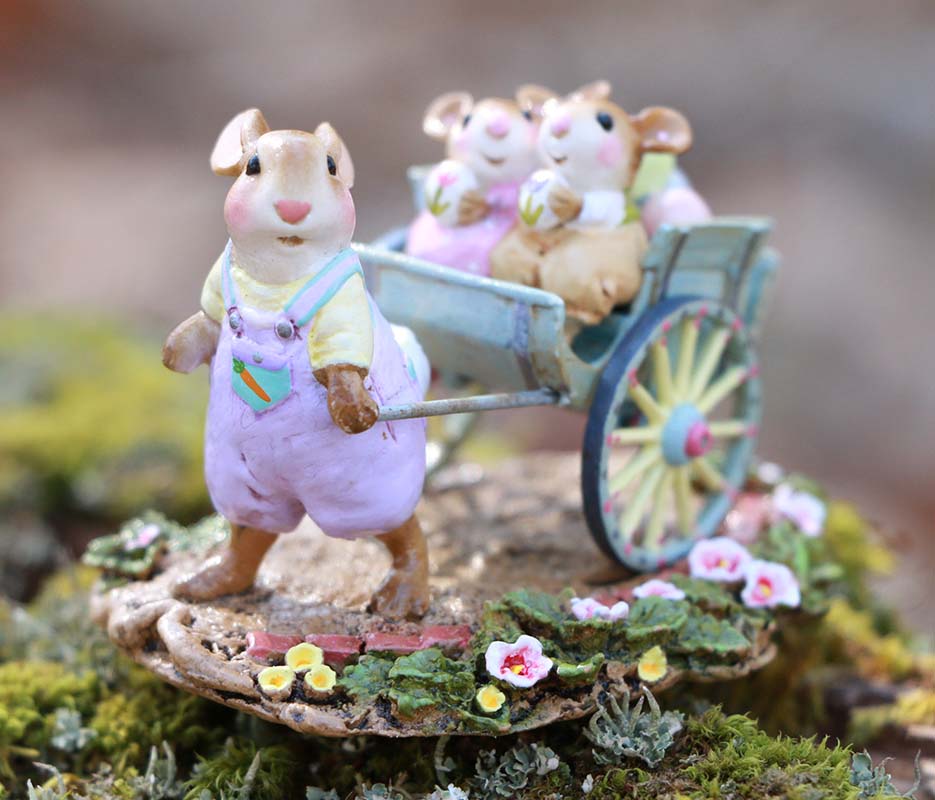 The Wee Forest Folk Tiny Collectible - Easter's on its Way (Not a Toy) features a charming mouse in purple overalls pulling a cart with two smaller mice, all hand sculpted and decorated for a whimsical, nature-inspired Easter scene.