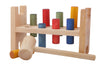 The Rainbow Pound -a- Peg is an eco-friendly wooden Montessori toy featuring colorful pegs and a mallet, designed for children to hammer the pegs through holes in the bench.
