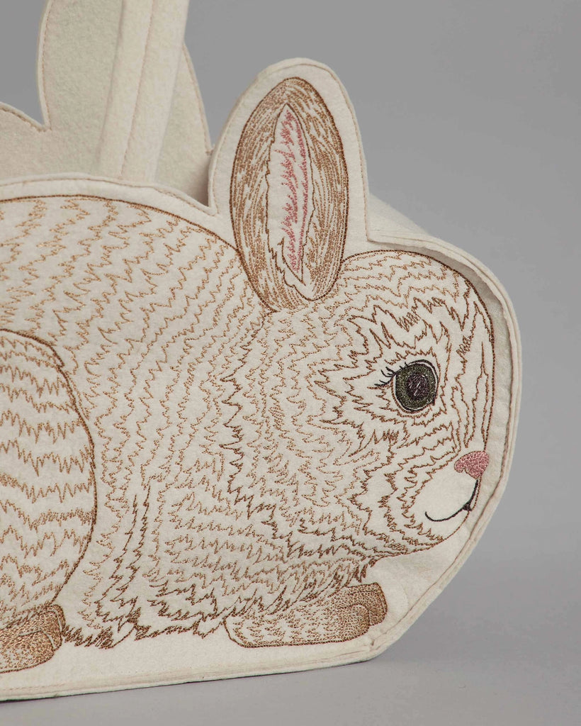 Sentence with Product Name: A close-up view of a Coral & Tusk Bunny Basket featuring detailed stitching and embroidered elements on a plain background. The bunny has a realistic eye and pink accents on its nose and ears.