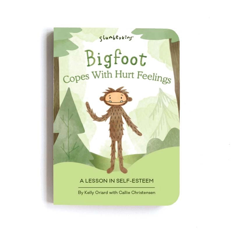 A book cover titled "Slumberkins Bigfoot Kin + Lesson Book On Self Esteem" by Kelly Oriard with Callie Christensen, featuring an illustration of Bigfoot standing among green trees, a theme of self-esteem.