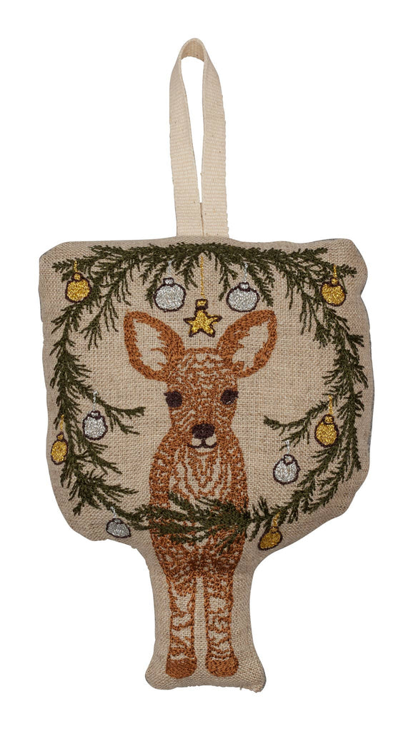 The Togetherness Deer Ornament is a decorative burlap wall hanging, showcasing an embroidered deer nestled within a Christmas wreath made of pine branches and embellished with gold and silver ornaments. It features a loop at the top for effortless display.