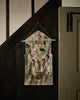 The Coral & Tusk Christmas Clock Advent Calendar, shaped like a house and decorated with trees and numbered pockets for treats, hangs on a dark wood wall by the staircase.
