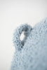 Close-up of a soft, pale blue Octopus Stuffed Animal with a looped fabric texture, focusing on a small, frayed edge against a blurred light background.