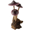 The Small Wooden Purple Mushroom Trio features three charming purple mushrooms with white spots and long stems, growing from a piece of brown driftwood—a delightful decorative figurine perfect for any space.