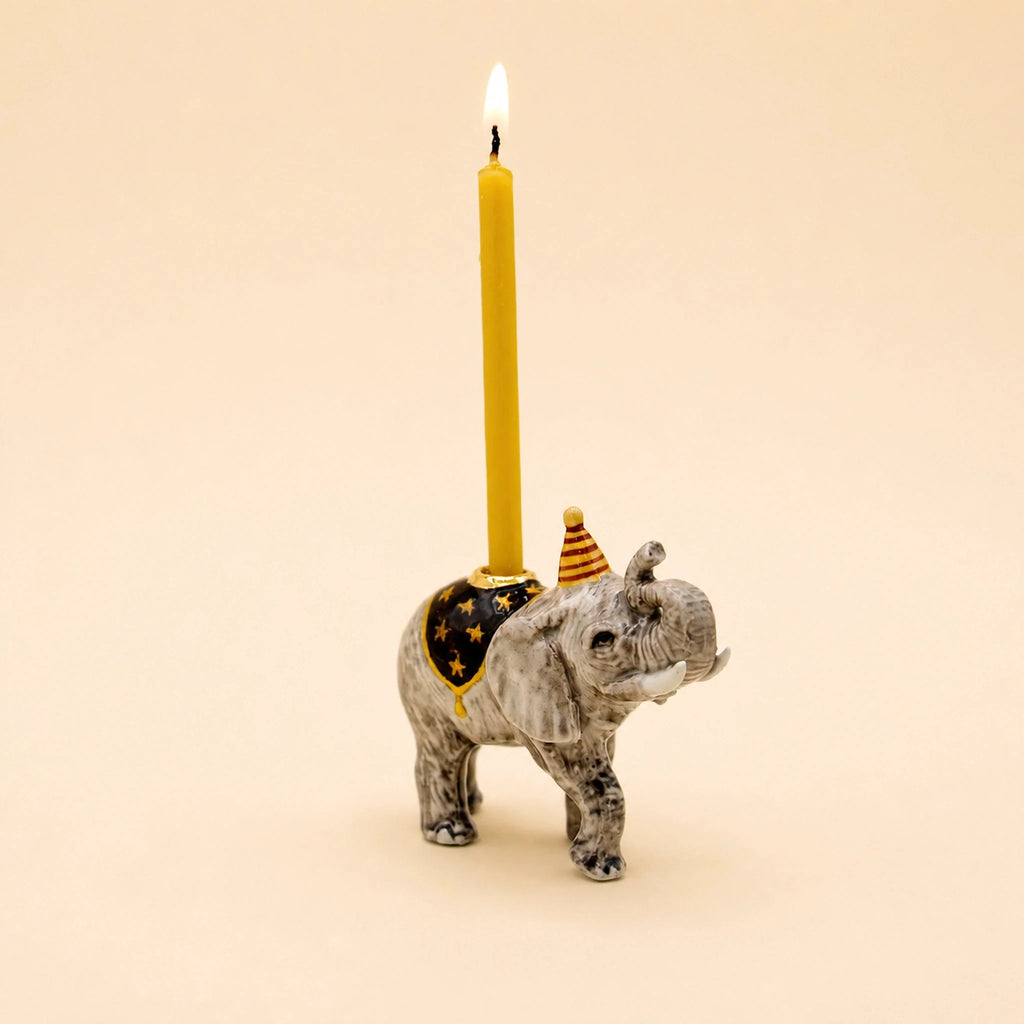 The Elephant Cake Topper - Final Sale (ships in one week) features a hand-painted elephant in a party hat and cloak, holding a yellow candle—an adorable collectible keepsake.