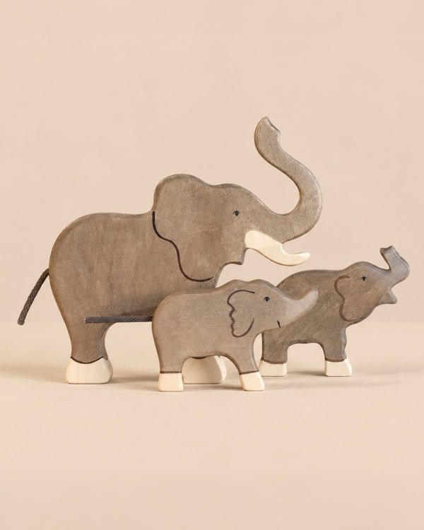 Holztiger Handmade Wooden Elephant Family Set consisting of three handcrafted wooden elephant figures of varying sizes, each with light-colored feet.