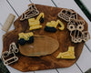 Cookies shaped like construction vehicles and matching wooden cutters from our Construction Cutter Set - Eco Playdough Tool are beautifully arranged on a wooden board, featuring a toy rolling pin and a road-shaped cookie in the center. This setup invites sensory play, making it ideal for little hands to explore baking or playdough activities on a crisp white table.
