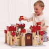 A young boy sits on the floor, smiling as he raises the gate of the Lionheart Wooden Castle—a beautifully crafted playset made from sustainable wood—perfect for hours of imaginative play.