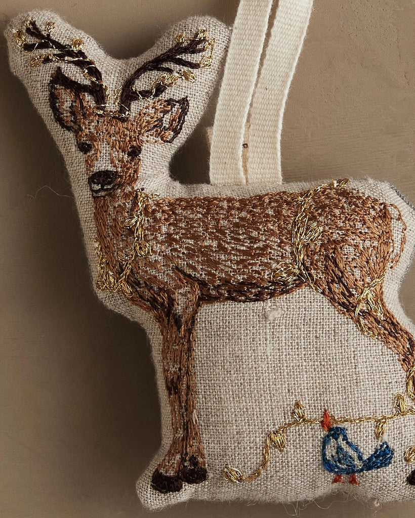 The Coral & Tusk Deer with Lights Ornament features a gold-embroidered deer, a small blue bird, and a gold vine on beige—an enchanting addition to your Christmas tree ornament collection.