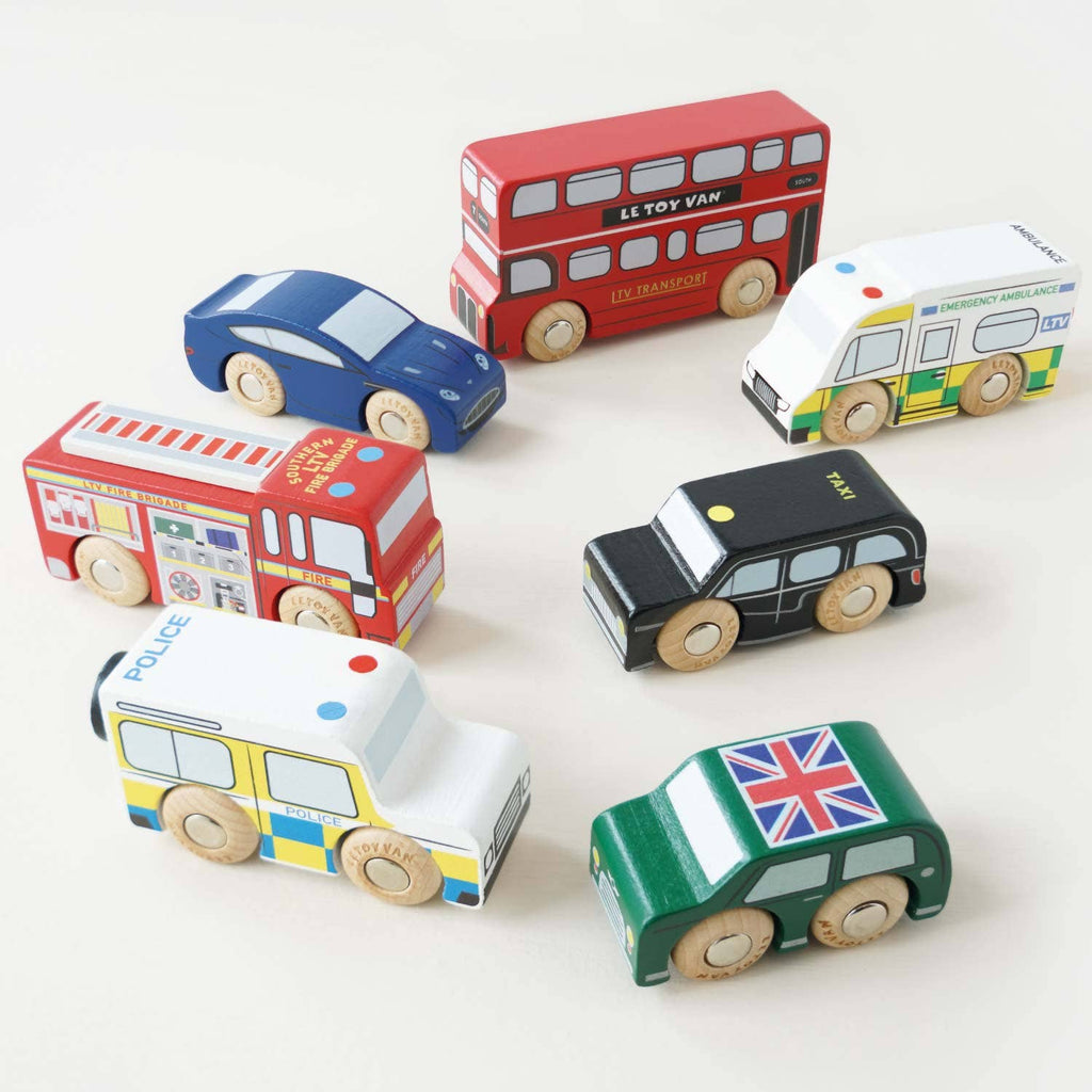 The London Toy Car Set features seven colorful wooden vehicles, including a red double-decker bus, police car, ambulance, fire truck, taxi, and more—ideal for imaginative play on any light surface.