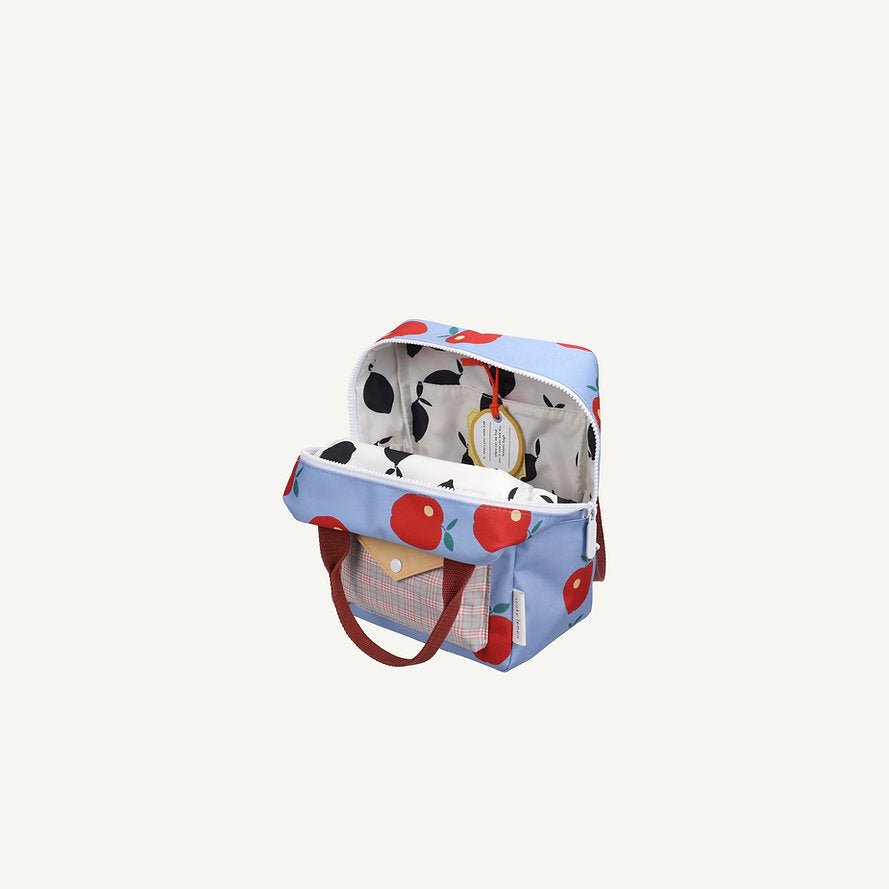 The Sticky Lemon Backpack Small - Special Edition - Apple Grub is a blue kids backpack with red apple patterns, brown handles, front pocket, white interior with fruit designs, an inner tag, and a waterproof lining from recycled PET bottles.