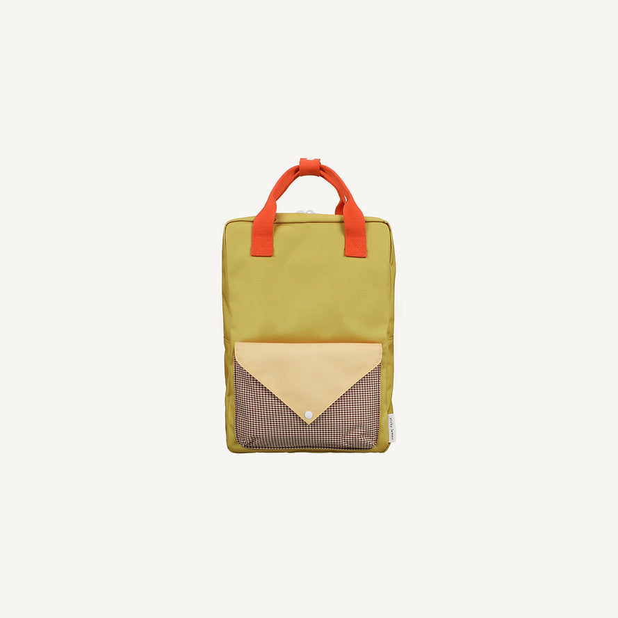 A rectangular kids backpack in Bookworm Green from Sticky Lemon, with red handles, a large front pocket featuring a beige flap and mesh detailing, made from recycled PET bottles, photographed against a plain white background.