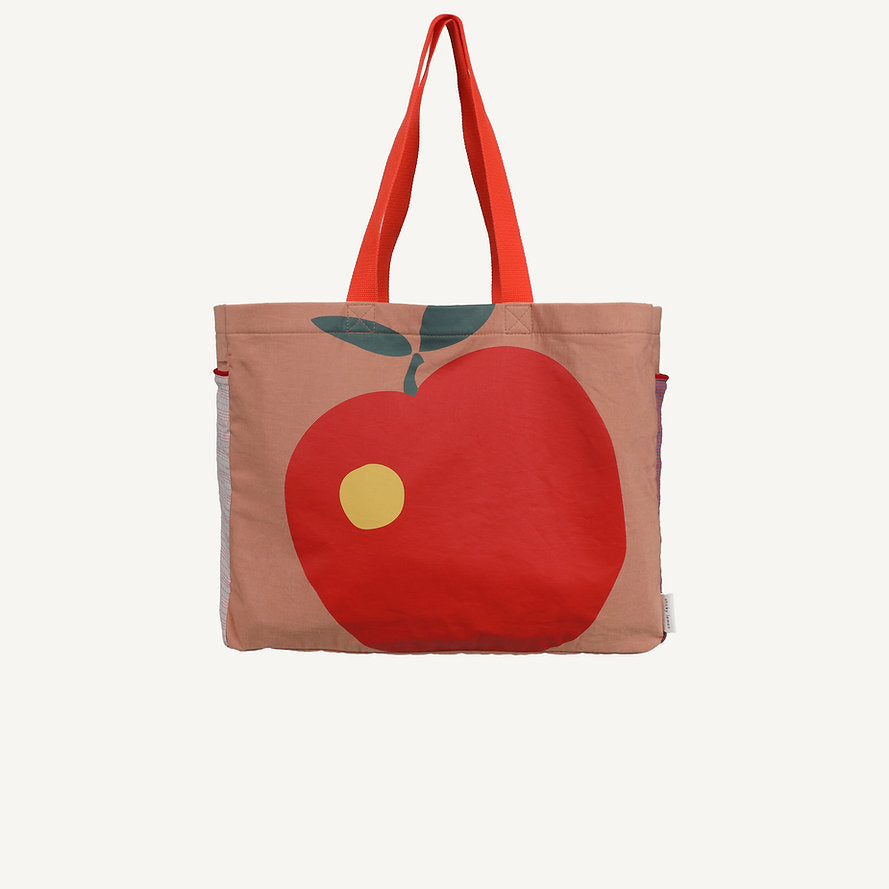 The Sticky Lemon Shopper - Apple is a tan colourblock tote with red handles, featuring a large red apple graphic with a green leaf and yellow spot on the front. The bold design stands out against any plain background.