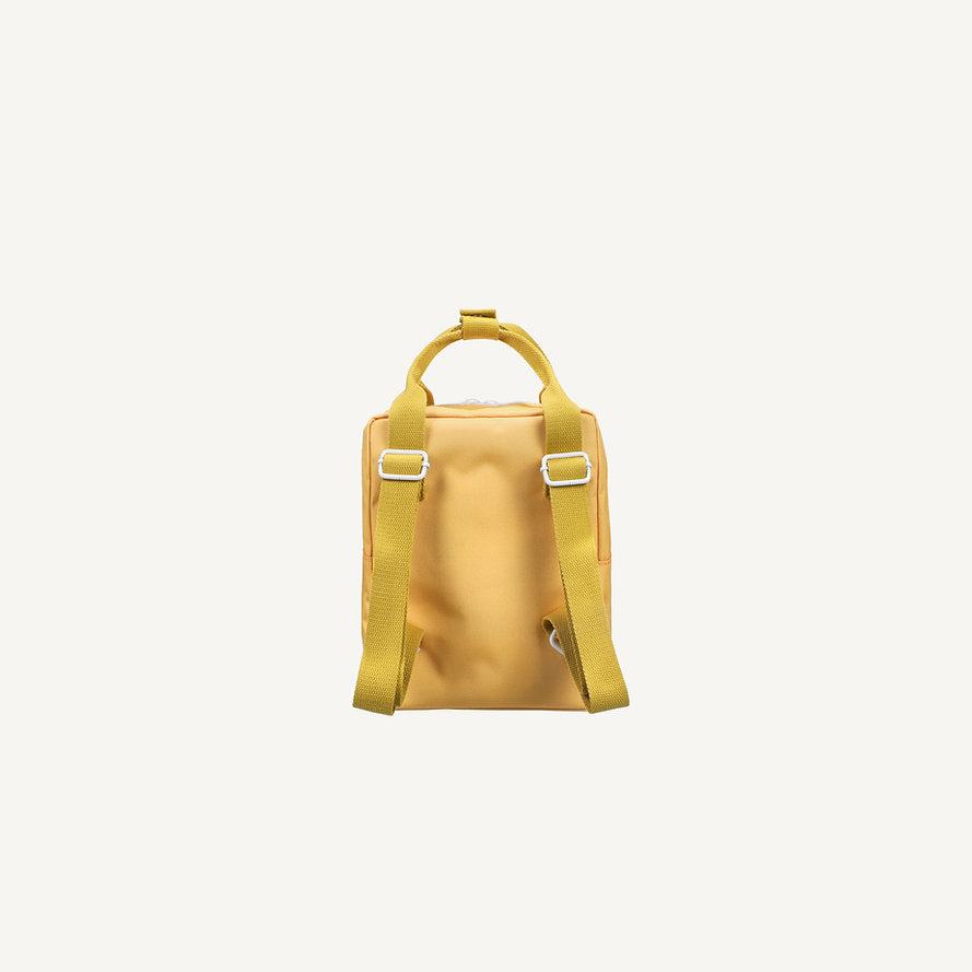The Sticky Lemon Backpack Small - Envelope - Apple Juice is shown from the back, highlighting its yellow color, two adjustable shoulder straps, top handle, and minimalist design against a plain white background.