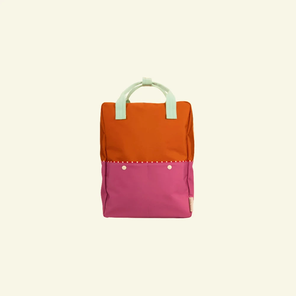 The Sticky Lemon Backpack Large | Color Blocking | Gravel Orange + Rosette Pink is a vibrant and playful accessory. It features a colorful design with an orange top and a pink bottom section, complemented by mint green adjustable shoulder handles for easy carrying. The white button details on the pink section add an extra touch of charm. Made from recycled PET bottles, this eco-friendly backpack also includes a waterproof lining for added practicality.