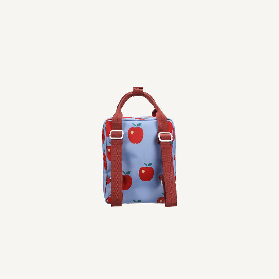The Sticky Lemon Backpack Small - Special Edition - Apple Grub is a compact blue kids backpack with red handles and straps, featuring a red apple pattern with green leaves. Made from recycled PET bottles, it has a waterproof lining and appears on a white background.