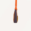 A side view of the Sticky Lemon Shoulder Bag | Leather Ball + Golden Cup, featuring an orange strap, brown body, dark purple panel, and crafted from recycled PET bags, set against a plain off-white background.