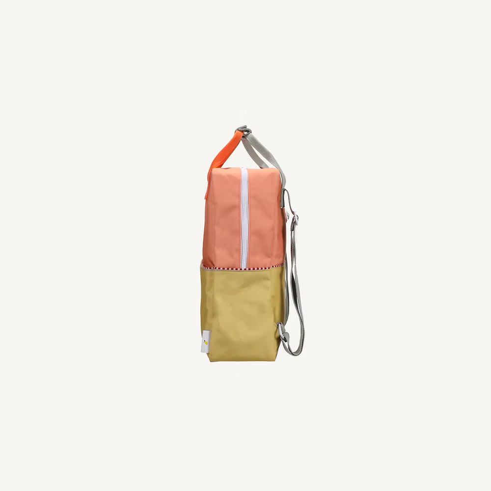 The Sticky Lemon Backpack Large | Color Blocking | Coral Pink + Reed Green features a side view with a coral pink top, reed green bottom, white zipper, patterned trim, silver adjustable strap, and waterproof lining for belongings.