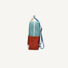 Side view of the Sticky Lemon Backpack Large | Color Blocking | Aquatic Green + Shipwreck Rust, made from recycled PET, featuring a teal upper, red lower section, blue adjustable strap, tan top handle, and waterproof lining on a white background.