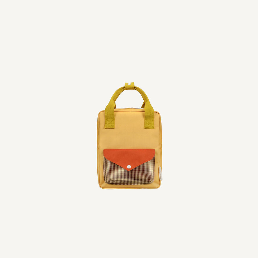 The Sticky Lemon Backpack Small - Envelope - Apple Juice is a yellow kids backpack with green handles, a front pocket with a red flap and brown-and-white checkered design, made from recycled PET bottles and shown on a plain white background.