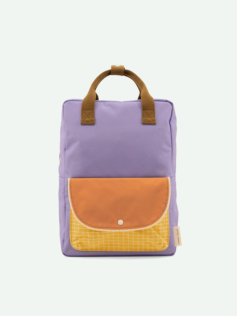 A lavender and mustard color-blocked Sticky Lemon Backpack Large with a large front pocket, smaller yellow checkered pocket, and brown Sticky Lemon handles, displayed against a white background.