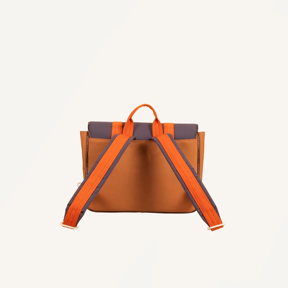 The Sticky Lemon School Bag | Better Together | Leather Ball is showcased from the back, featuring a brown design with orange and dark purple accents. It is crafted from waterproof nylon and includes two orange shoulder straps along with a small orange handle at the top. The background is plain white.