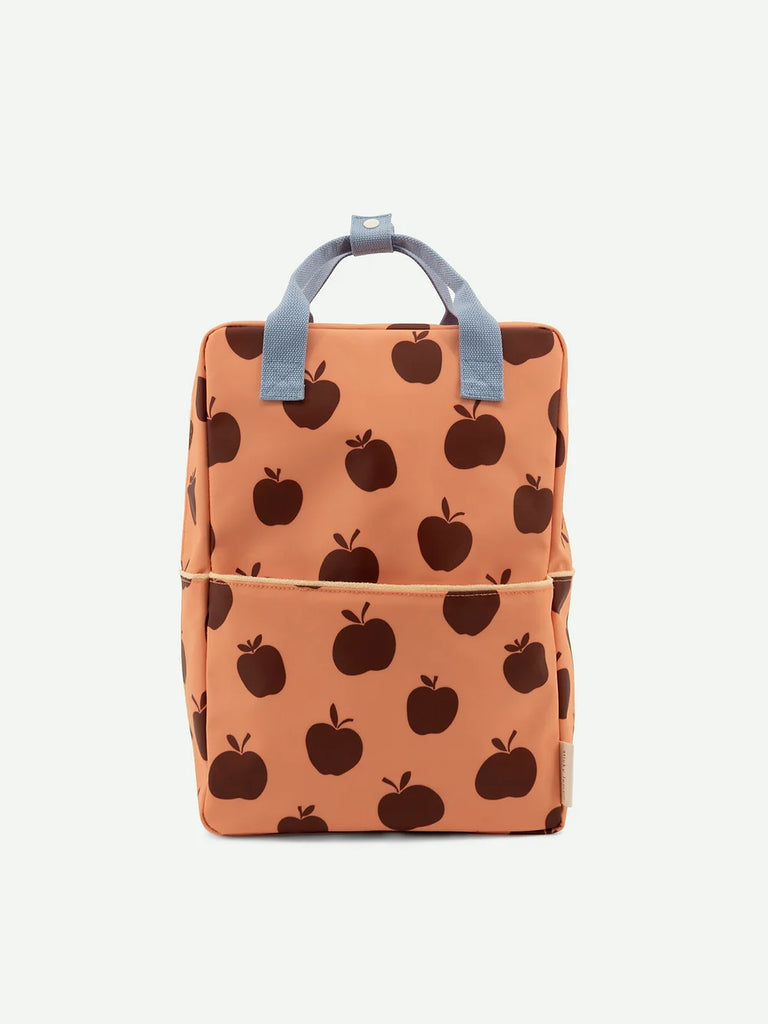 A trendy Sticky Lemon Backpack Large | Special Edition with a peach-colored background and a repeating pattern of dark brown apple prints, featuring a prominent top handle, a front pocket, and YKK zippers.