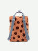 A stylish orange Sticky Lemon Backpack Large | Special Edition adorned with a pattern of black apple silhouettes, featuring blue straps and a waterproof lining, presented in a front view on a white background.