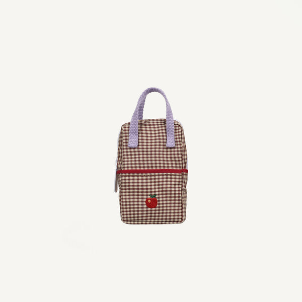 The Sticky Lemon Backpack Mini - Gingham Tree features a small rectangular shape with a brown and white checkered pattern, a red front zipper, purple handles, and a charming red apple patch on the lower front. Capturing Sticky Lemon's playful style, this mini backpack for dolls is displayed against a plain white background.