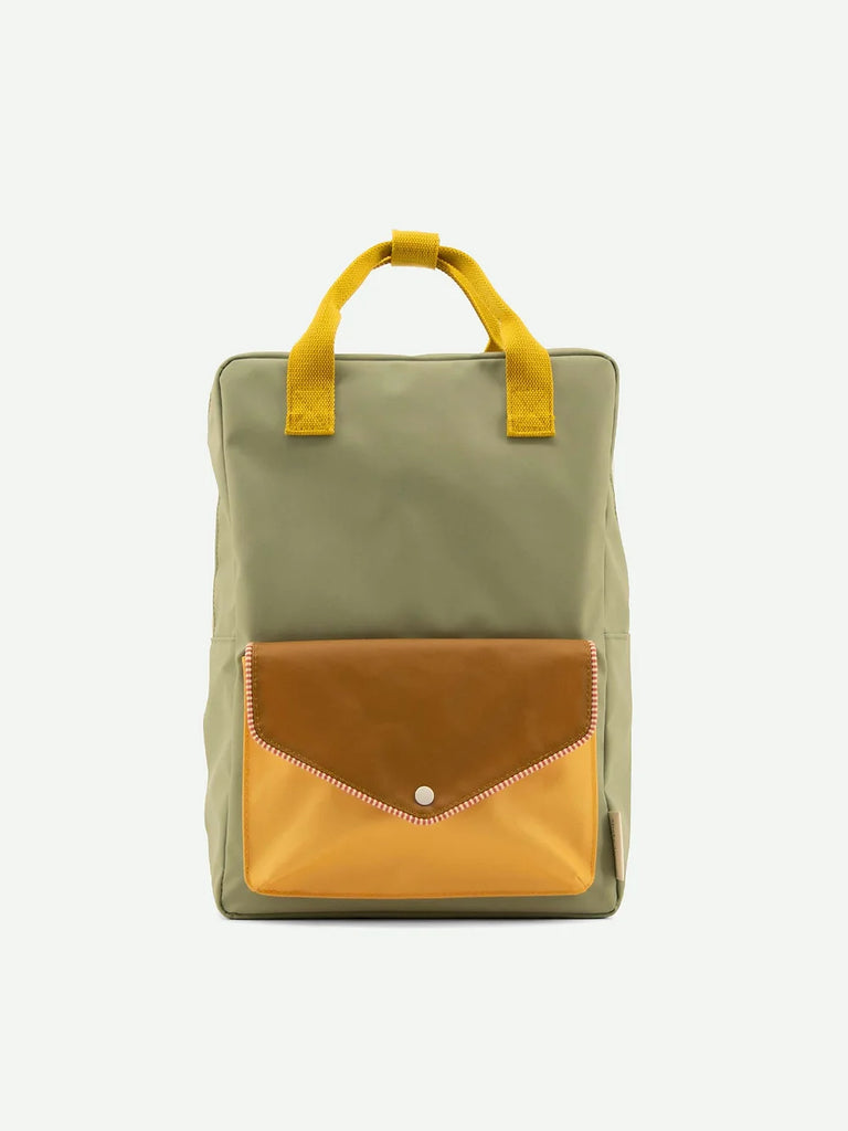 A stylish Sticky Lemon Backpack Large | Envelope Collection | Map Green with a muted green body and a contrasting mustard yellow top handle. It features a large orange flap pocket in the front. The background is plain white.