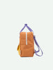 Sticky Lemon small, orange backpack made from waterproof nylon with violet straps and a yellow banana peeking out from a side pocket, isolated against a white background.